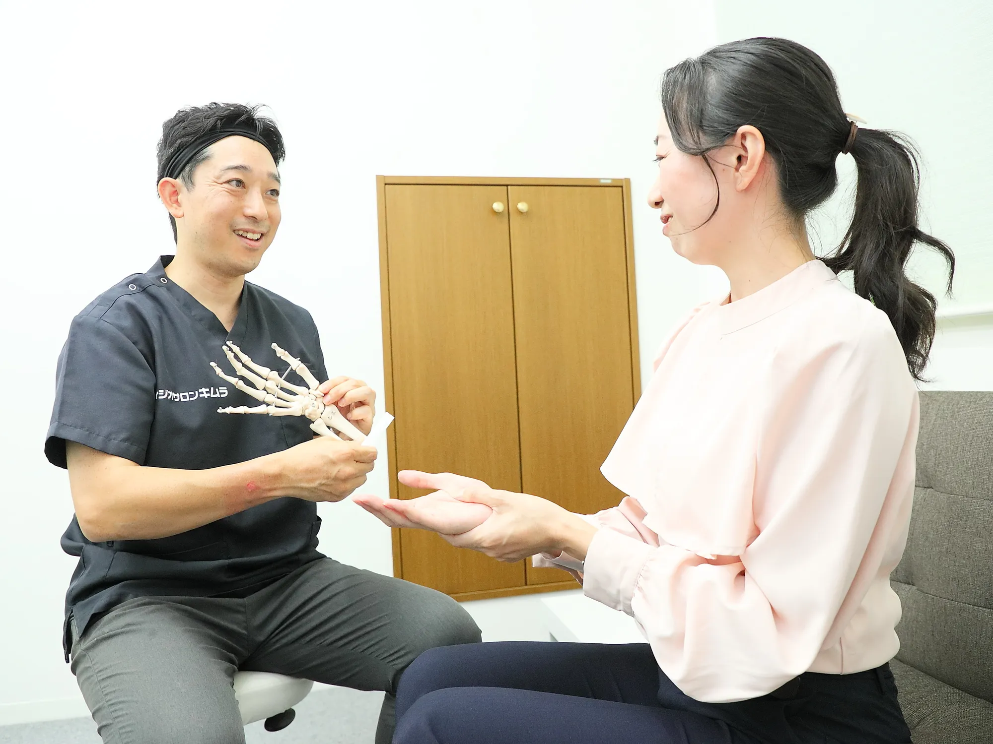 初回のカウンセリングで、手の模型を使ってお客様に説明する理学療法士の木村